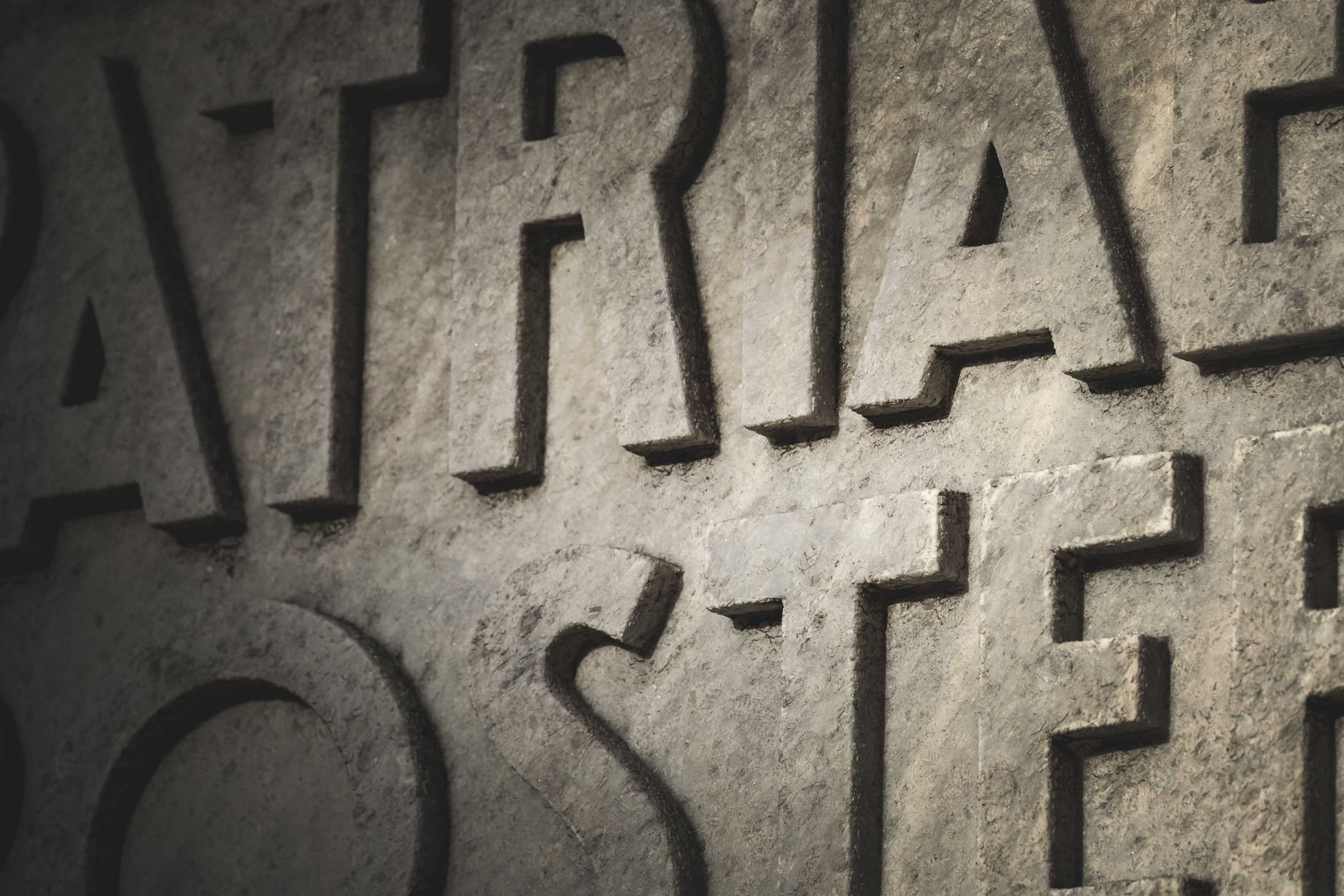 A stonemason cutting lettering into a stone slab